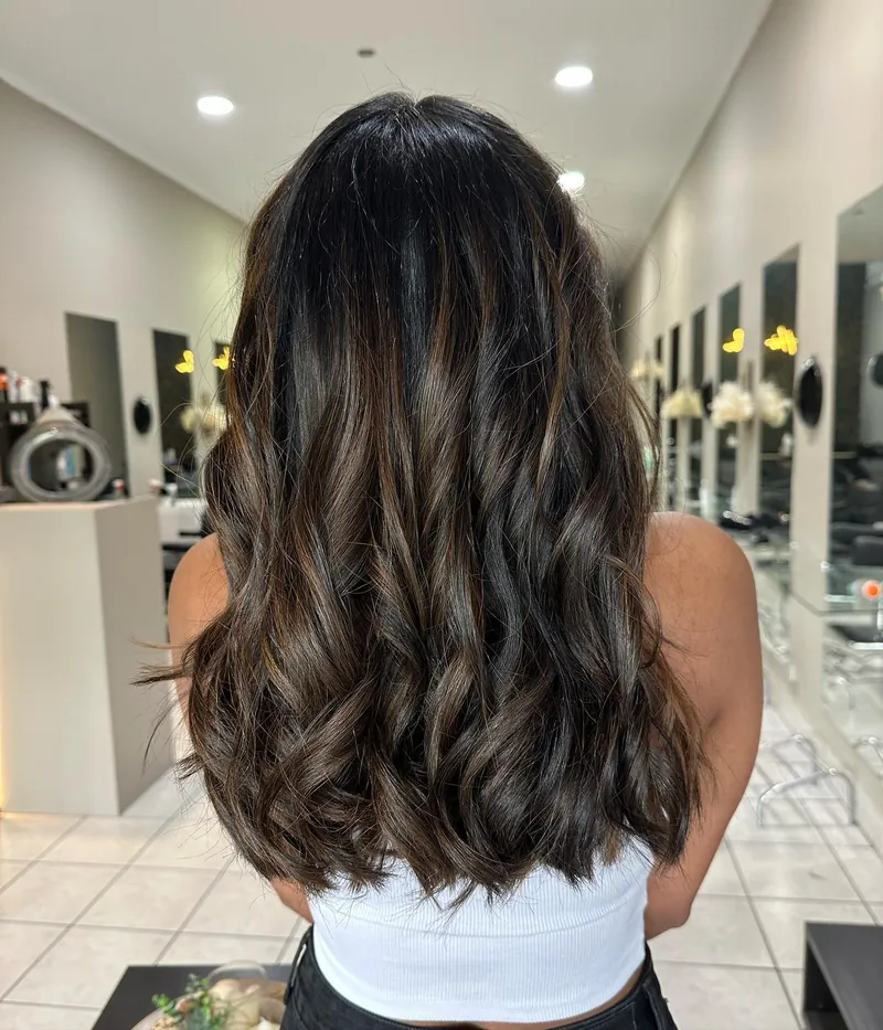 Dark brown hair with caramel pieces, curled into loose waves, from behind