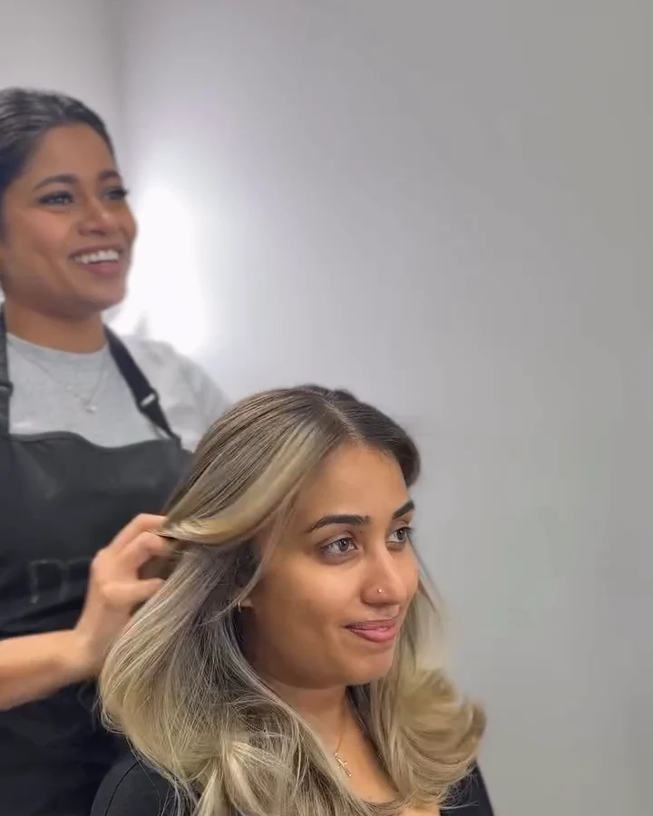 Oshi laughing behind a client as she sees her new soft, dimensional blonde for the first time