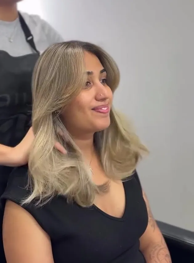 A client with a bright, creamy blonde with a soft root, being styled